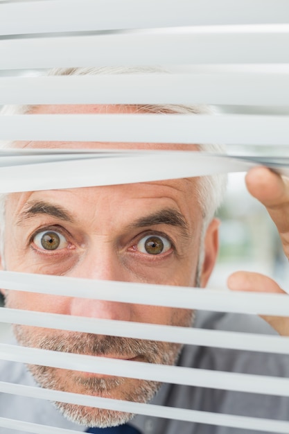 Closeup of a serious businessman peeking through blinds