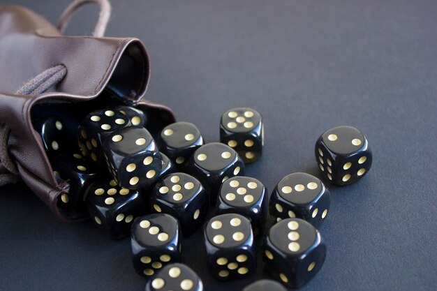 Closeup set of gaming dice rolled out of leather bag on dark background Top view