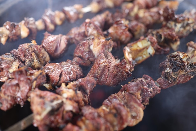 Closeup of several skewers with grilled juicy meat in smoke