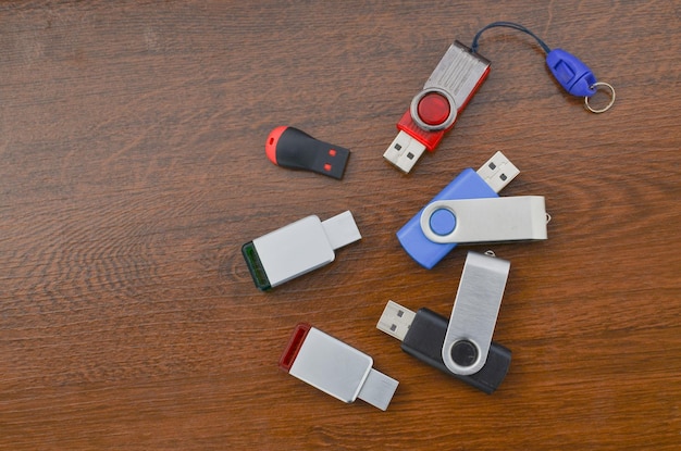 Крупный план нескольких USB-накопителей на деревянном столе Несколько разных USB-накопителей Флэш-накопители, представляющие мобильное хранилище и передовые технологии