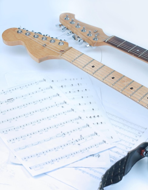 Primo piano spartiti e chitarra su sfondo bianco