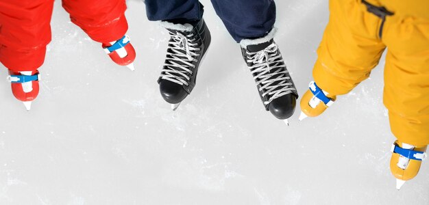 Primo piano delle scarpe di papà e bambini che pattinano sulla pista di pattinaggio sul ghiaccio