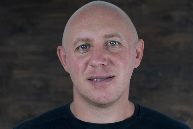 Closeup shoot of middle-aged caucasian bald man looking straight at camera. People and lifestyle concept. Portrait of middle aged man indoors