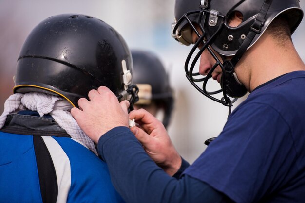 Colpo del primo piano del giocatore di football americano che controlla i caschi al campo