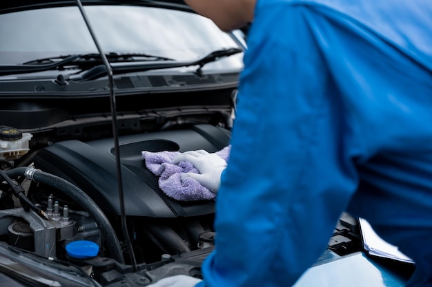 Closeup shot of an Asian mechanic's hand in a blue shirt writing on a paper in an auto repair shop