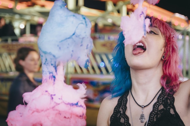 Closeup shot of an attractive young female enjoying eating cotton candy in an amusement park