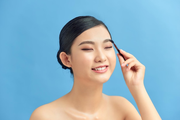 Closeup shot of beautiful woman applying eyeshadow on eyelid using makeup brush