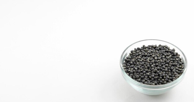 Closeup shot of black lentils in a glass container on a white background