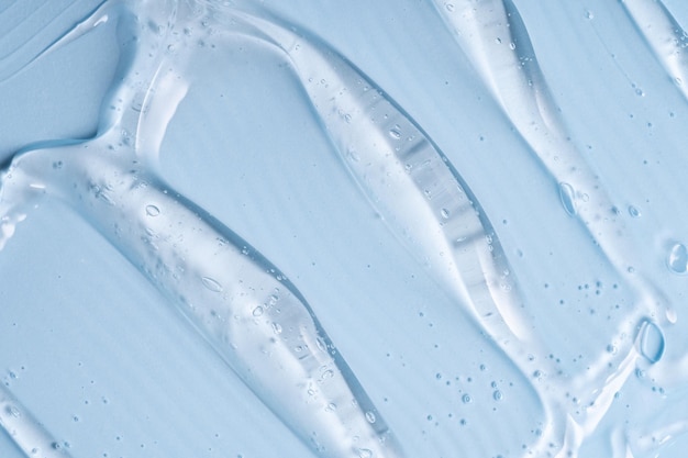closeup shot of blue liquid cosmetic gel or serum makeup swatches with a glossy shiny texture on a smooth blue background