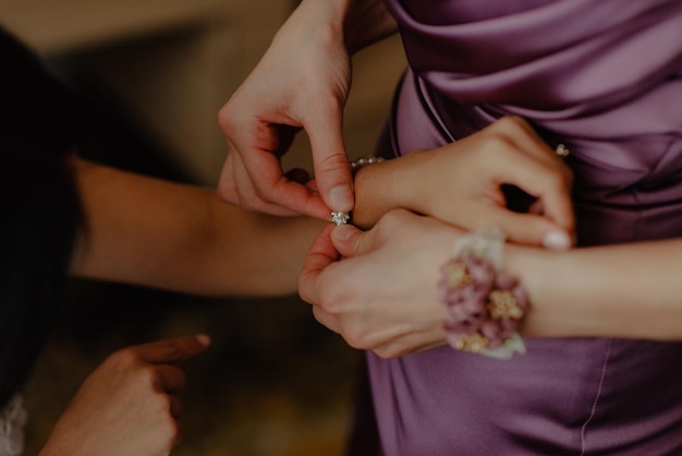 Closeup shot of a bridesmaid putting on the bride's bracelet