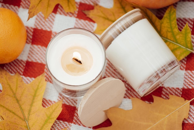 Closeup shot of burning candle and some yellow leaves around Autumn mood aromatic candles calm atmosphere