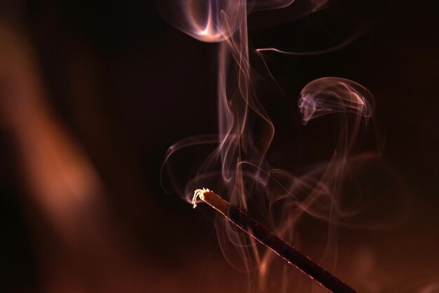 Photo closeup shot of a burning incense stick on a dark background