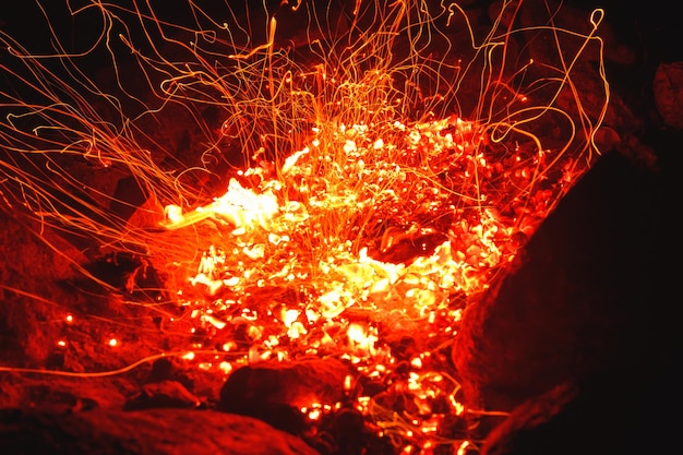 Closeup shot of campfire brightly burning at night throwing sparkles