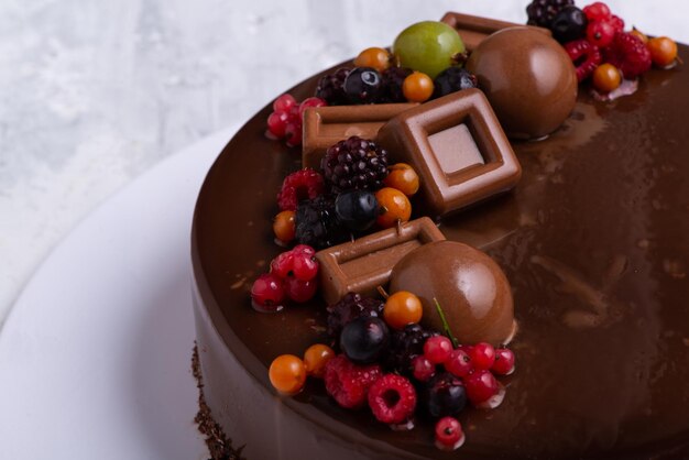 Colpo del primo piano di una torta di glassa al cioccolato decorata con frutti di bosco