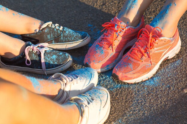 Foto colpo del primo piano dei piedi femminili variopinti con la polvere blu di holi sull'asfalto