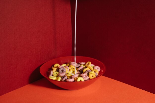 Closeup shot of colourful cereals in a red bowl with milk pouring into it on red corner background