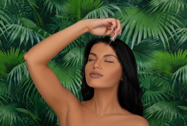 Closeup shot of cosmetic oil applying on young woman's face with pipette Grey background Caucasian