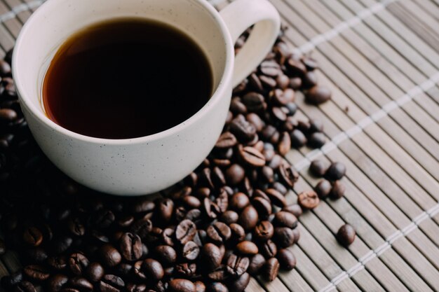 Closeup shot of a cup of coffee with coffee beans