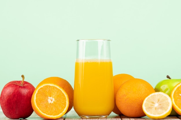 Closeup shot of a cup of invigorating juice surrounded by fruits on a wooden table