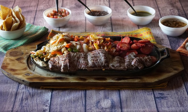 맛있는 파릴라다, 나무 표면에 있는 한 접시에 있는 다른 종류의 고기의 클로즈업 샷