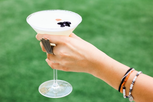 Closeup shot of a female hand holding a martini glass with a white cocktail beverage