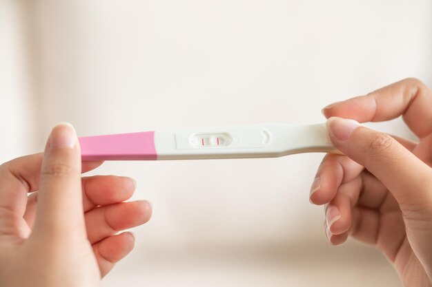 긍정적 인 임신 테스트 를 들고 있는 여자 손 의 클로즈업 사진
