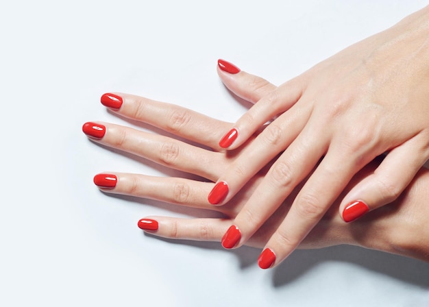 Снимок крупным планом женских рук с красным лаком для ногтей