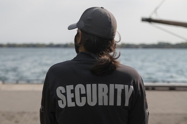 Photo closeup shot of a female security guard in uniform and mask watching over the harbor area