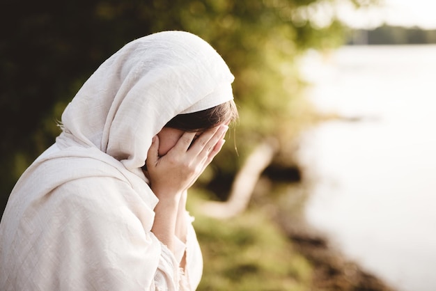 울고 있는 성서적 가운을 입은 여성의 클로즈업 샷 - 죄를 고백하는 개념