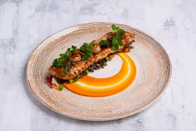 A closeup shot of a Fish course with salmon meat herbs and orange sauce on a marble plate