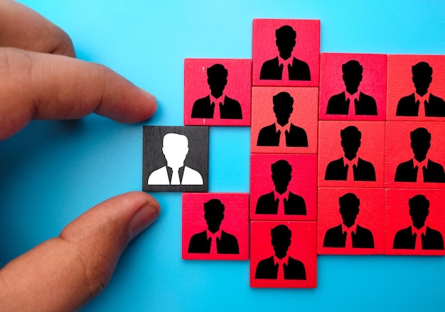 Photo closeup shot of a hand holding squares with an old employee and new employee icons