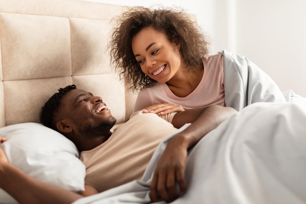 Closeup shot of happy black spouses cuddling flirting in bed