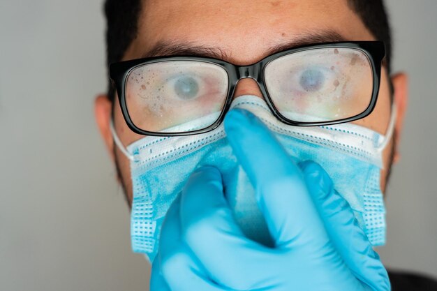 Closeup shot of a Hispanic man wearing a blue disposable face mask and looking at the camera