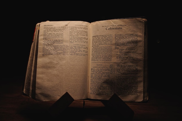 Closeup shot of a historic old Bible open on the Colossians pages on display in a dark room