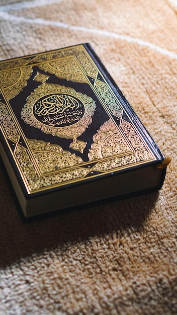 Снимок крупным планом исламской книги Коран с золотой арабской каллиграфией слева