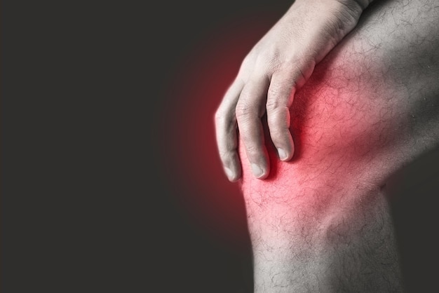 Closeup shot of the knee of a person with a hurting point on a black background