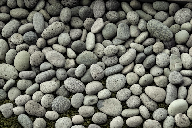 Closeup shot of light gray pebbles on the green grass background