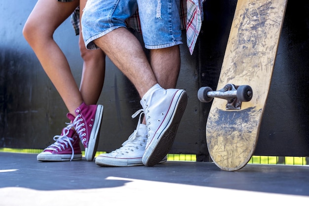 Closeup shot of male and female teens next to each other in the park with a skateboard