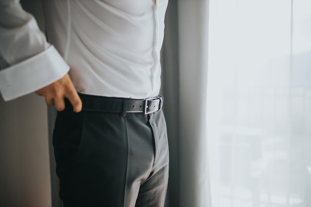 Closeup shot of a male hand correcting his belt - wedding preparation