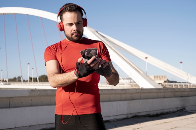 A closeup shot of a male in red headphones using his mobile while jogging in the street