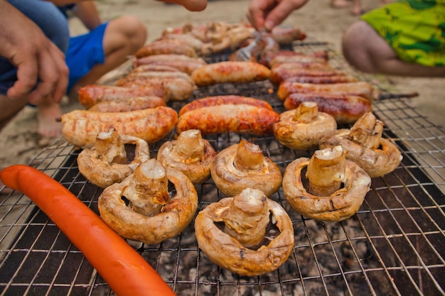 Крупным планом мужчина жарит грибы и шашлык