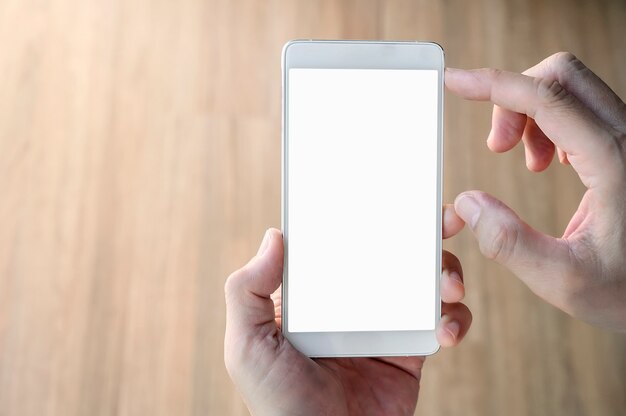 空白の画面を持つ白いスマートフォンを持っている人間の手のクローズアップショット。