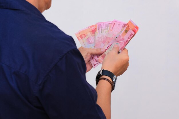 Photo closeup shot of man holding some rupiah money in his hands