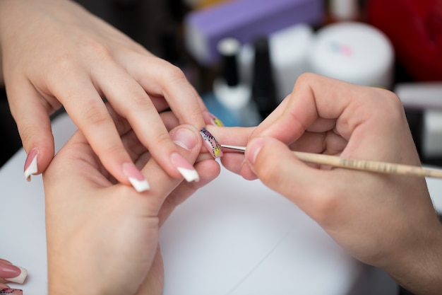 Uomo del colpo del primo piano che fa manicure alla donna nel salone di bellezza