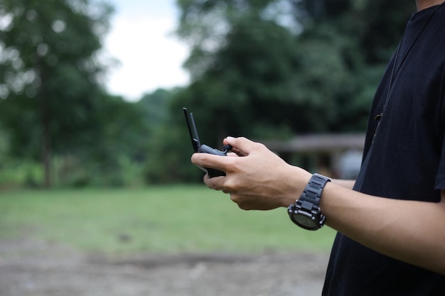 Primo piano di un uomo che opera o naviga con il drone tramite telecomando nel parco verde