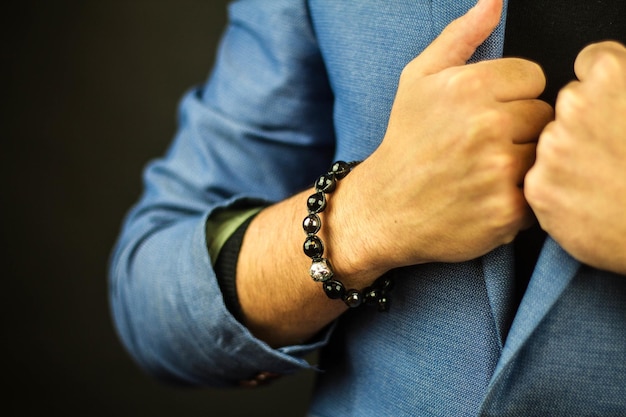 Photo closeup shot of a man in a suit wearing a beautiful bracelet made of stones