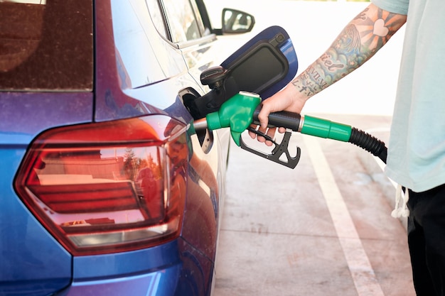 Closeup shot of a man with a tattoo pumping gasoline