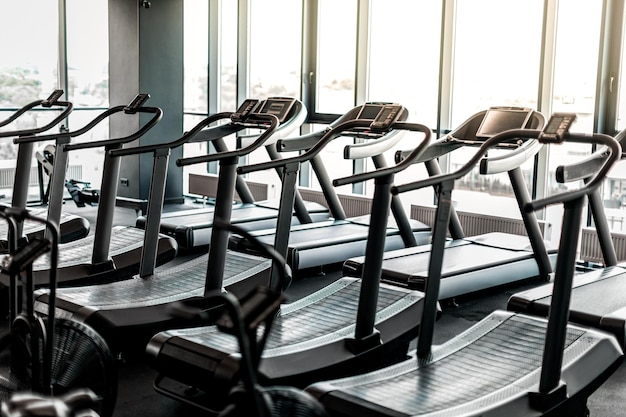 Photo closeup shot of modern treadmills standing in row at empty gym