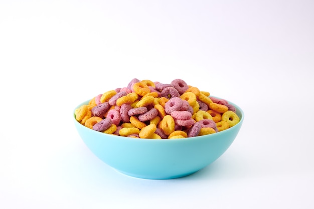 Closeup shot of multicolored fruity cereals in a blue bowl isolated on white background