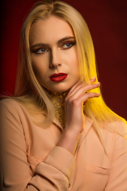 Фото Снимок крупным планом роскошной модели с ярким макияжем и золотой фольгой. красный и желтый студийный свет